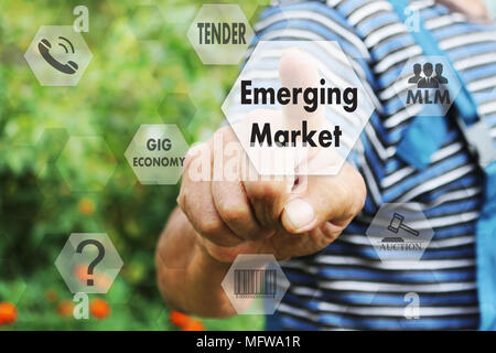 The elderly businessman chooses emerging market, presses a button on the touch screen Stock Photo