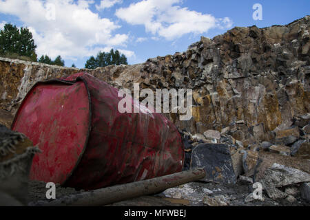 Basalt pillars. Red metal barrel. Stone excavation. Heavy industry Stock Photo