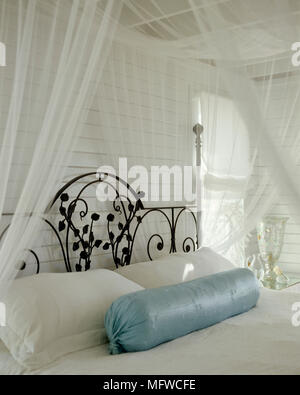 Wrought iron double bed in country style room with white sheer bed canopy Stock Photo