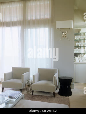 Two armchairs in front of large picture windows Stock Photo - Alamy