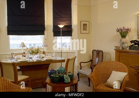 A modern, open plan sitting room with dining area, cream walls, table, chairs, brown roman blinds, Stock Photo