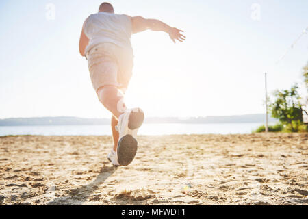 Outdoor cross-country running in summer sunshine concept for exercising, fitness and healthy lifestyle. Close up of feet of a man running in grass Stock Photo
