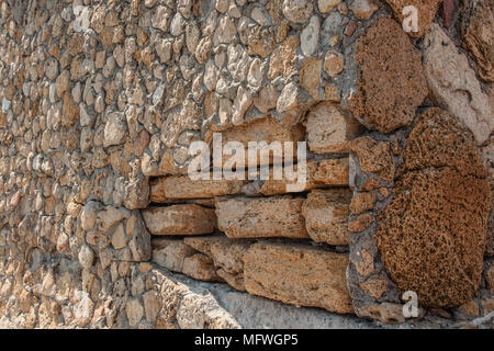 Background of natural multi-colored stone on a plain textured wall with cracks close up Stock Photo
