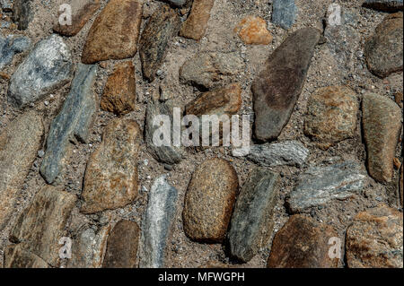 Background of natural multi-colored stone on a plain textured wall with cracks close up Stock Photo