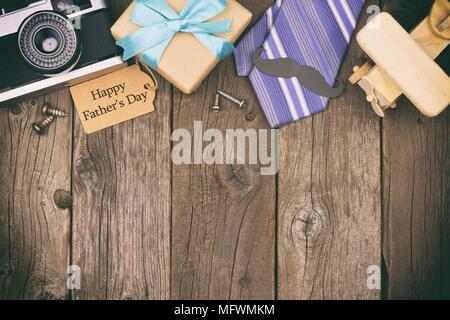Happy Fathers Day gift tag with top border of gifts, ties and decor on a rustic wood background. Top view, vintage styling. Stock Photo