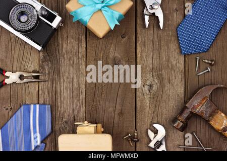 Fathers Day theme frame of gifts, ties and tools on a rustic wood background. Top view with copy space. Stock Photo