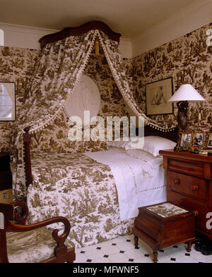 Double bed with canopy in Toile de Jouy fabric and coordinated wallpaper Stock Photo