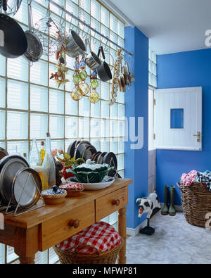 Kitchen pots and pans hanging on wall above table with drawers Stock Photo