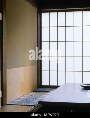 Japanese style dining room with large opaque window next to wooden bench and table Stock Photo