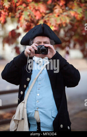 An amusing photo of an actor in  18 century costume using a 21st-century digital camera in colonial Williamsburg Virginia Stock Photo