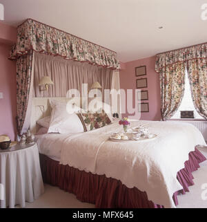 Double bed with fabric canopy in pink bedroom Stock Photo