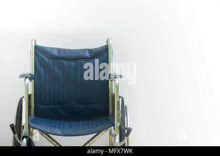 Empty wheelchair parked in hospital on white wall background. Stock Photo