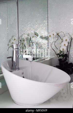 Water running from tap into bowl washbasin on modern bathroom Stock Photo