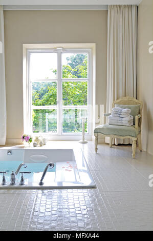 Sunken bathtub in spacious tiled bathroom Stock Photo