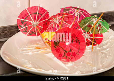 Empty white cake plate, plate on a kitchen plate with colorful paper decoration umbrella. Stock Photo