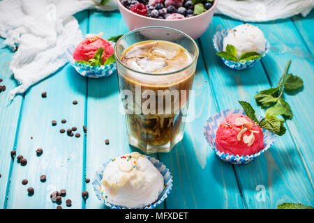 Iced coffee in glass and ice cream on blue wood background. Stock Photo