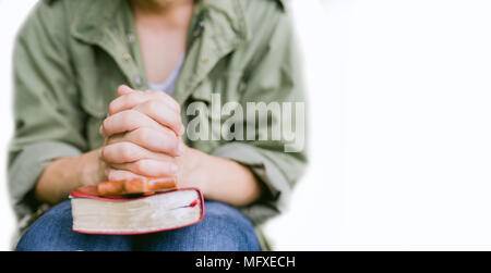 man praying on holy bible in the morning.teenager boy hand with Bible praying,Hands folded in prayer on a Holy Bible in church concept for faith, spir Stock Photo