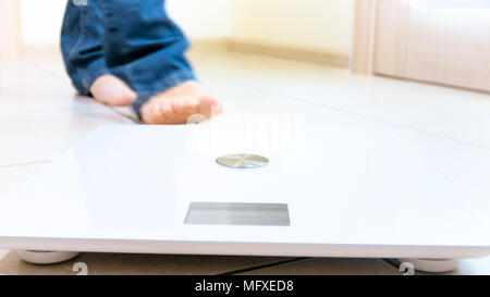 Closeup photo of barefoot person in jeans walking towards floor scales Stock Photo