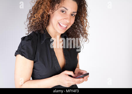Pretty woman using mobile device looking at the viewer on isolated white background Stock Photo