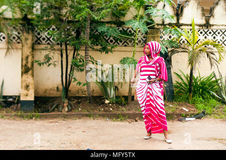 Woman waiting for a bus in Kimeri Avenue, Msasani, Dar es Salaam Stock Photo