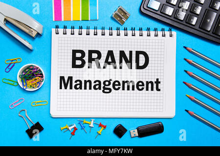 Notebook with Notes BRAND Management with office tools on a blue background . Concept BRAND Management Stock Photo
