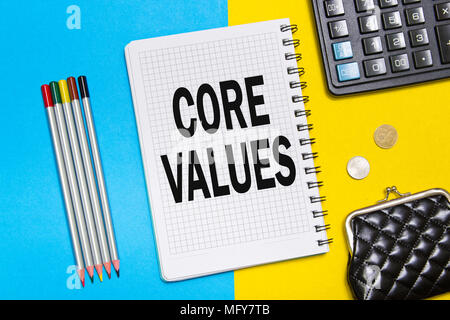 Notebook with notes CORE VALUES with office tools on a blue an yellow background . Concept CORE VALUES Stock Photo