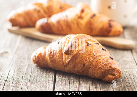 Croissant with chocolate crumbs on old wooden table. Stock Photo