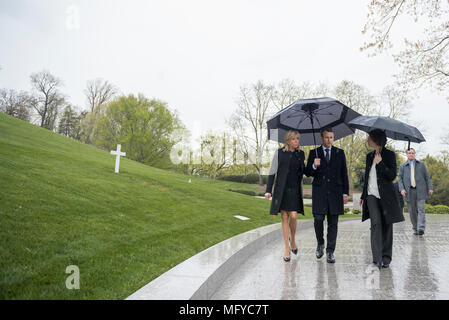 French President Emmanuel Macron, center, and his wife Brigitte Macron, are escorted by superintendent Katharine Kelley, right, during a visit to the gravesite of Robert F. Kennedy on a rainy day at Arlington National Cemetery April 24, 2018 in Arlington, Virginia. Stock Photo