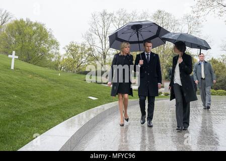 French President Emmanuel Macron, center, and his wife Brigitte Macron, are escorted by superintendent Katharine Kelley, right, during a visit to the gravesite of Robert F. Kennedy on a rainy day at Arlington National Cemetery April 24, 2018 in Arlington, Virginia. Stock Photo