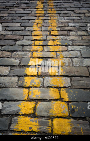 Yellow stripes painted on a cobblestone roadway Stock Photo
