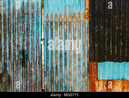 Old rusted corrugated blue gate, grungy texture or background. Gate shut with a lock. Stock Photo