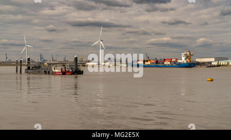 Gravesend, Kent, England, UK - September 23, 2017: View at the River Thames with wind turbines, a cargo ship and harbour cranes in the background Stock Photo