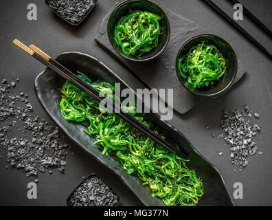 Seaweed wakame salad served with chopstick on black background Stock Photo
