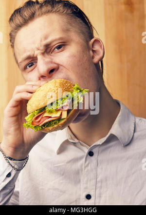 the young guy is really trying to burger and looking at camera Stock Photo