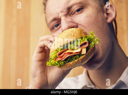 the young guy is really trying to burger and looking at camera Stock Photo