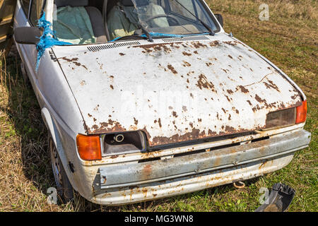 Old car wreck fit for scrap on a meadow Stock Photo