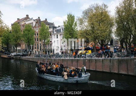 Amsterdam, Netherlands - 27 April, 2017: Local people and tourists dressed in orange clothes ride on boats and participate in celebrating King's Day a Stock Photo