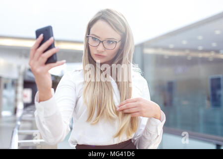Young blonde businesswoman taking selfie in business center, indoors Stock Photo