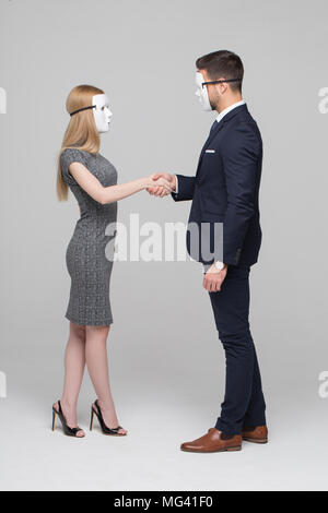 Young anonymous businesspeople in mask handshake on gray background Stock Photo