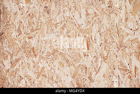 Fiberboard. Compressed light brown wooden plywood texture. Close up surface of pressed wood-shaving plate. Old wooden board bagasse background. Stock Photo