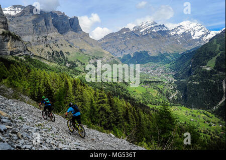 Two mountain bikers ride a trail across a scree slope near the town of Leukerbad in Valais, Switzerland. Stock Photo