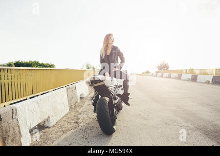 Beautiful woman biker posing sitting on a motorbike Stock Photo