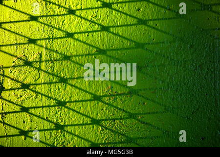 Metal Wire Fence Shadow on Green Concrete Wall Background. Stock Photo