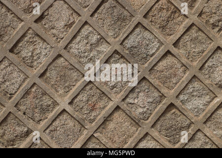 Patterned stone wall with squares set diagonally like a lattice. This wall is sand colored, would make good background. Slight shadows, daylight. Stock Photo