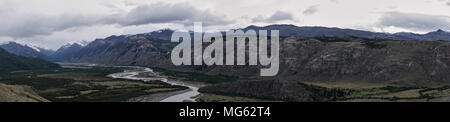 Argentinian Patagonia landscape. River flowing and mountain range in the background and an cloudy sky. Panorama. Extreme Wide shot. Stock Photo