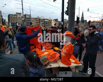 Amsterdam, The Netherlands - April 27th, 2018 : King's Day - Street vendor selling orange gear; King's Day (formerly Queen's Day) festivities invite locals and visitors alike to soak up Amsterdam's open-air fun. In the streets, canals, parks and everywhere in between, the city is bursting with orange as Amsterdammers enjoy the biggest street party of the year.;  Credit: Bala Divakaruni/Alamy Live News Stock Photo