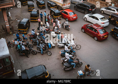 a group of Indian men on scooters waiting to turn at a busy intersection in Goa, India