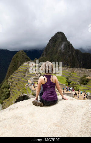 Young woman meditating above Machu Picchu Inca citadel in Peru Stock Photo