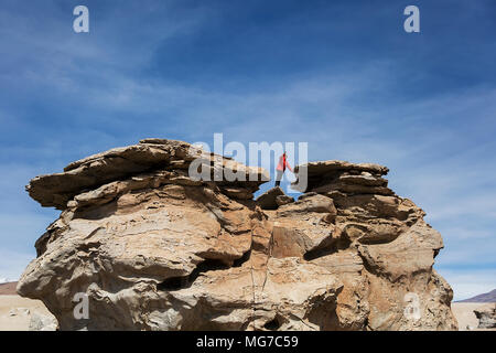 Young man at rock formations of Dali desert in Bolivia at Eduardo Avaroa Andean Fauna National Reserve in Bolivia Stock Photo