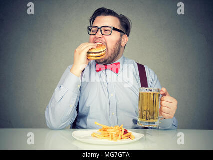 Business man eating junk food drinking beer Stock Photo